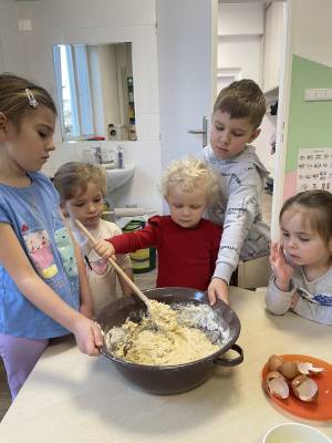 Děti u stolečku zadělávají těsto na  koblihy